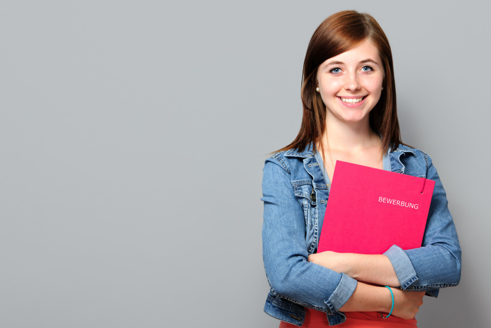 Young woman holding job application on grey background