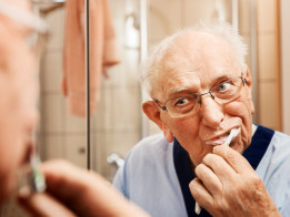 Älterer Herr im Bad beim Zähneputzen